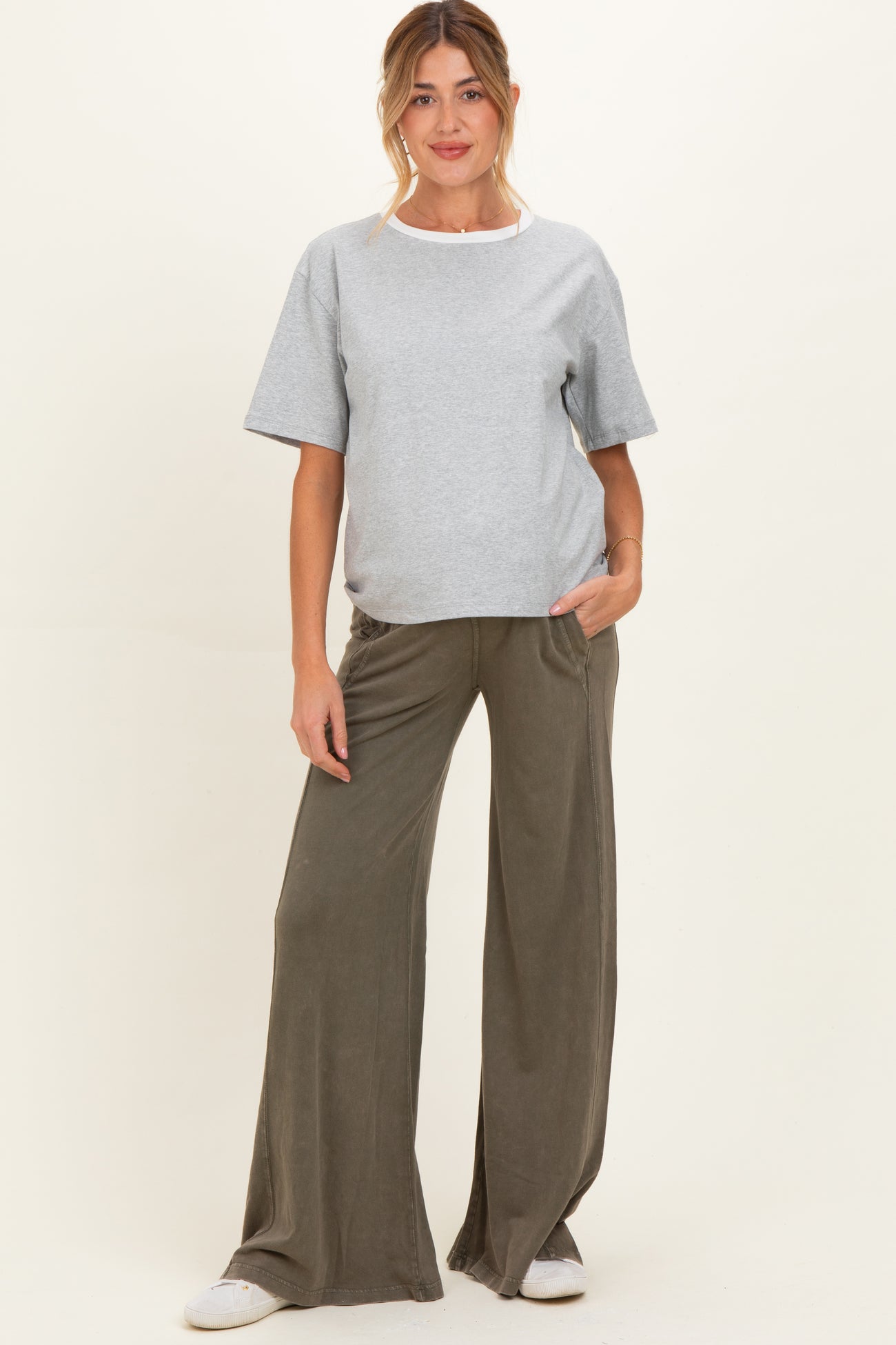 woman wearing a grey maternity t-shirt and olive green wide leg pants, standing with hands in pockets