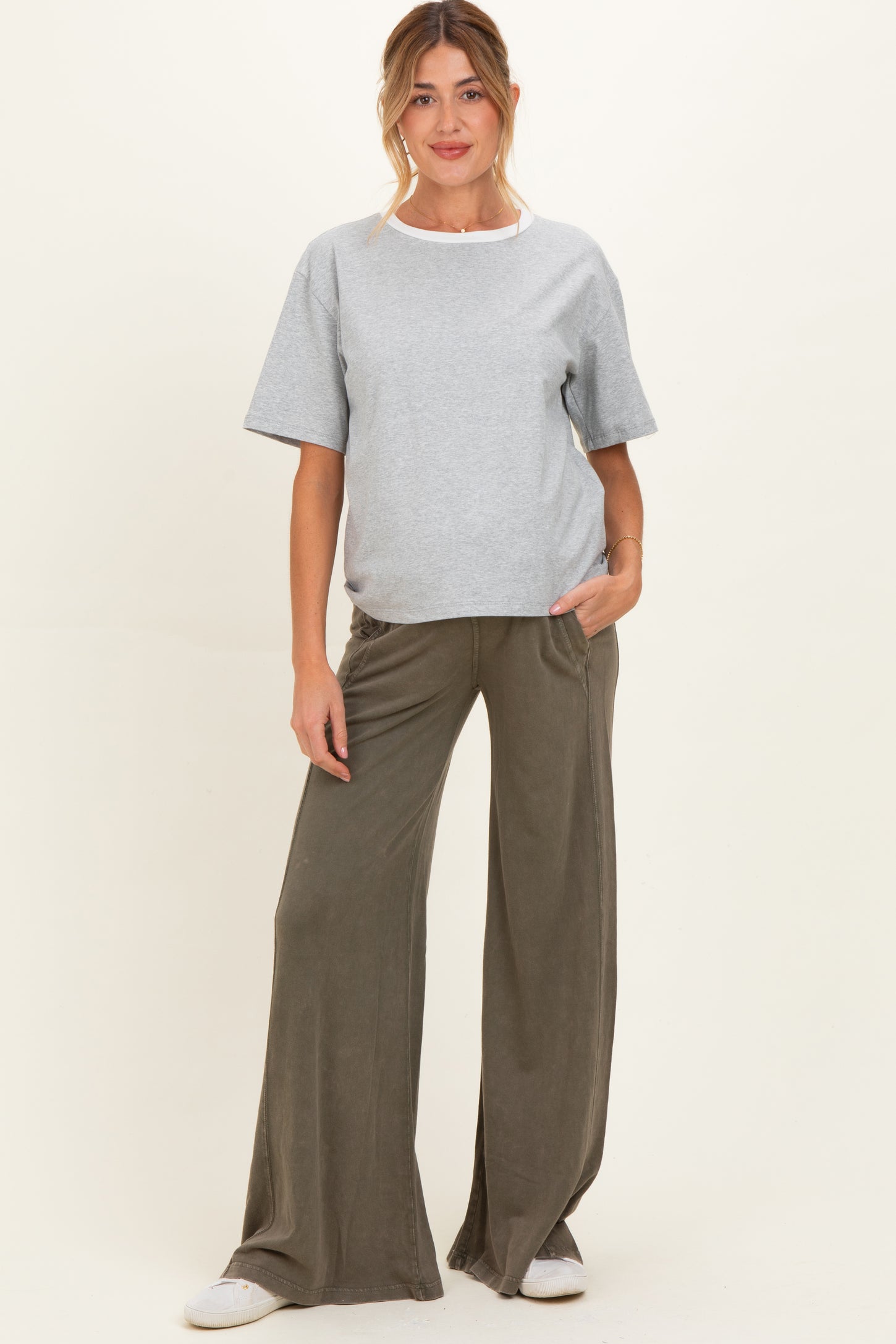 woman wearing a grey maternity t-shirt and olive green wide leg pants, standing with hands in pockets