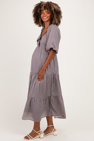 woman wearing a black and white gingham maternity dress with puff sleeves and a tiered skirt, showing her baby bump