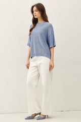 woman wearing a light blue oversized sweater with short sleeves and white wide-leg trousers