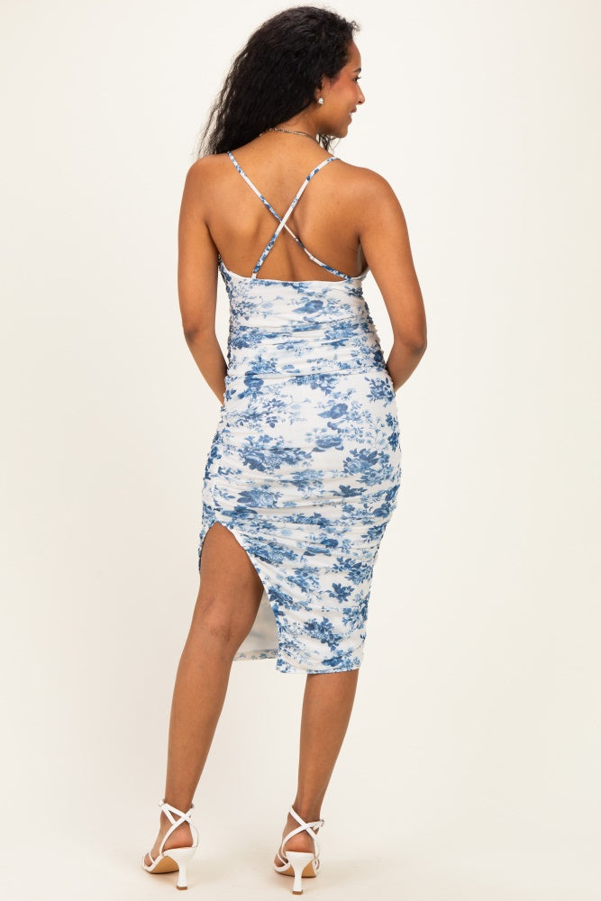 woman wearing a blue floral print maternity dress with a cross-back design and a side slit