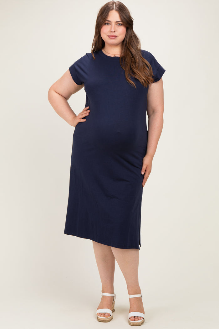 woman wearing a navy blue maternity plus dress with short cap sleeves and a relaxed fit, showcasing her baby bump
