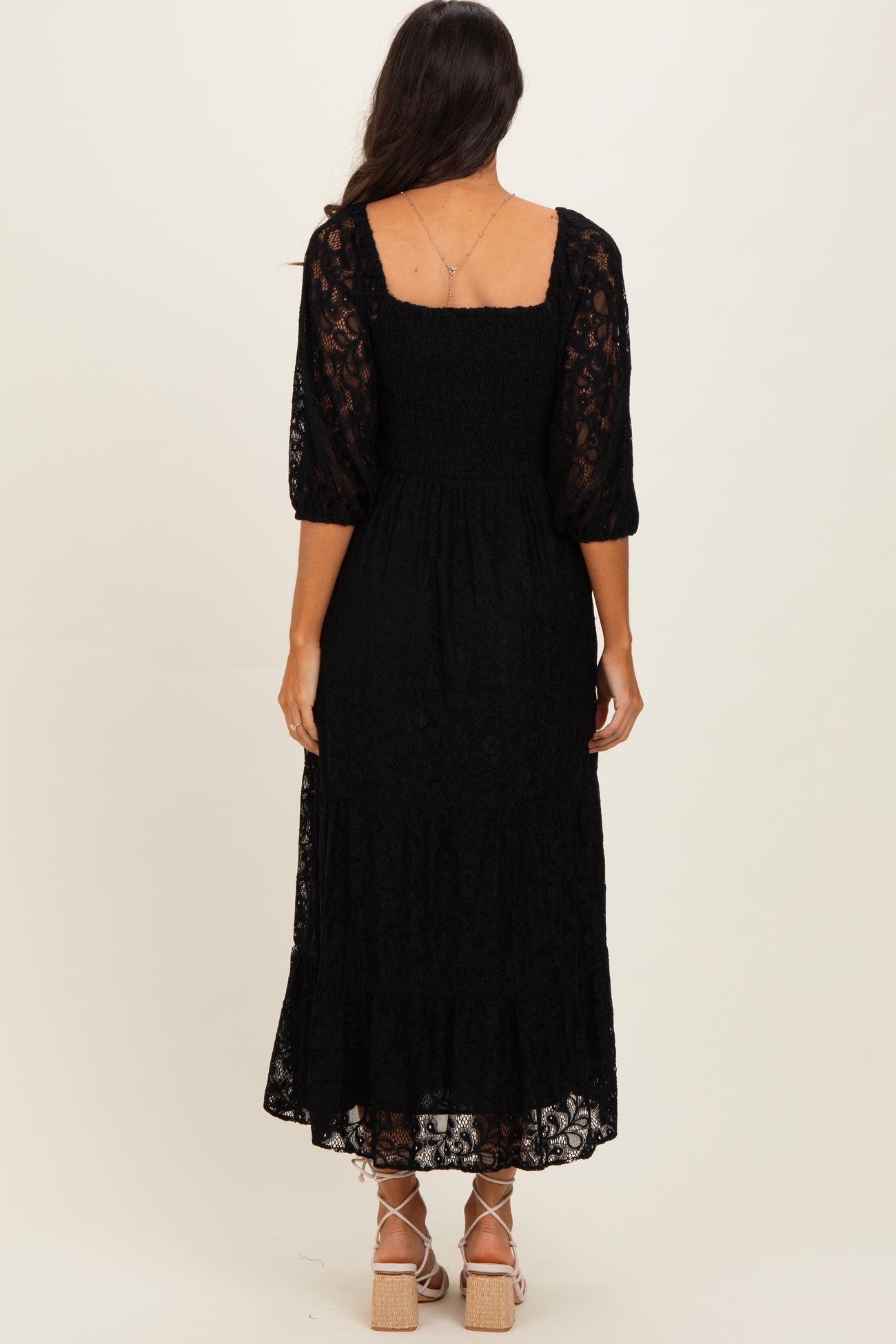 woman wearing a black lace maxi dress with puff sleeves and a smocked back detail