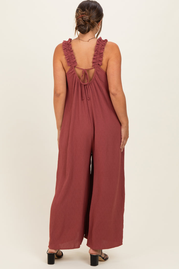 woman wearing a rust-colored maternity jumpsuit with ruffled straps and an open back