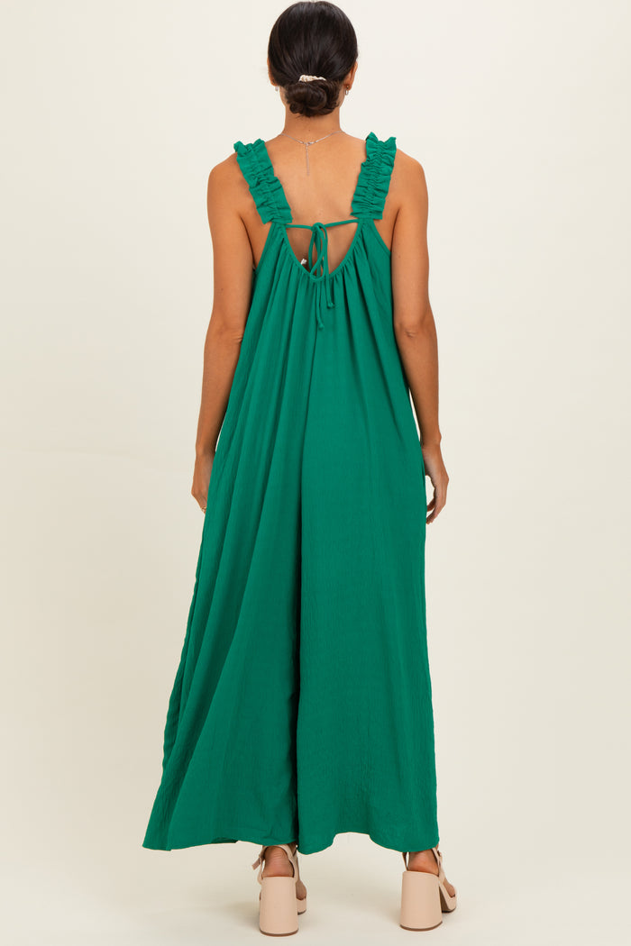 woman wearing a green sleeveless maxi dress with ruffle straps and an open back detail