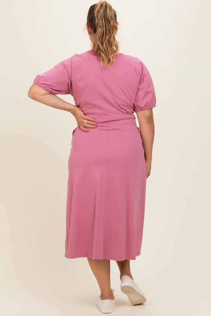 woman wearing a pink maternity plus dress with short puff sleeves and a flowy skirt, view from the back