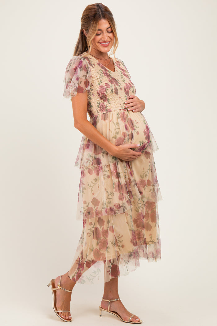 woman wearing a floral tiered maternity dress with a v-neckline, gently holding her baby bump