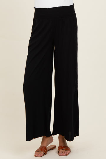 woman wearing black wide-leg maternity pants with a stretchy waistband and sandals