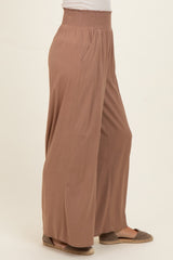 woman wearing a taupe wide-leg pant with a smocked waist and side pockets, styled with flat shoes