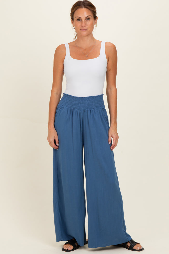 woman wearing a white sleeveless top and blue wide-leg pants with a smocked waistband