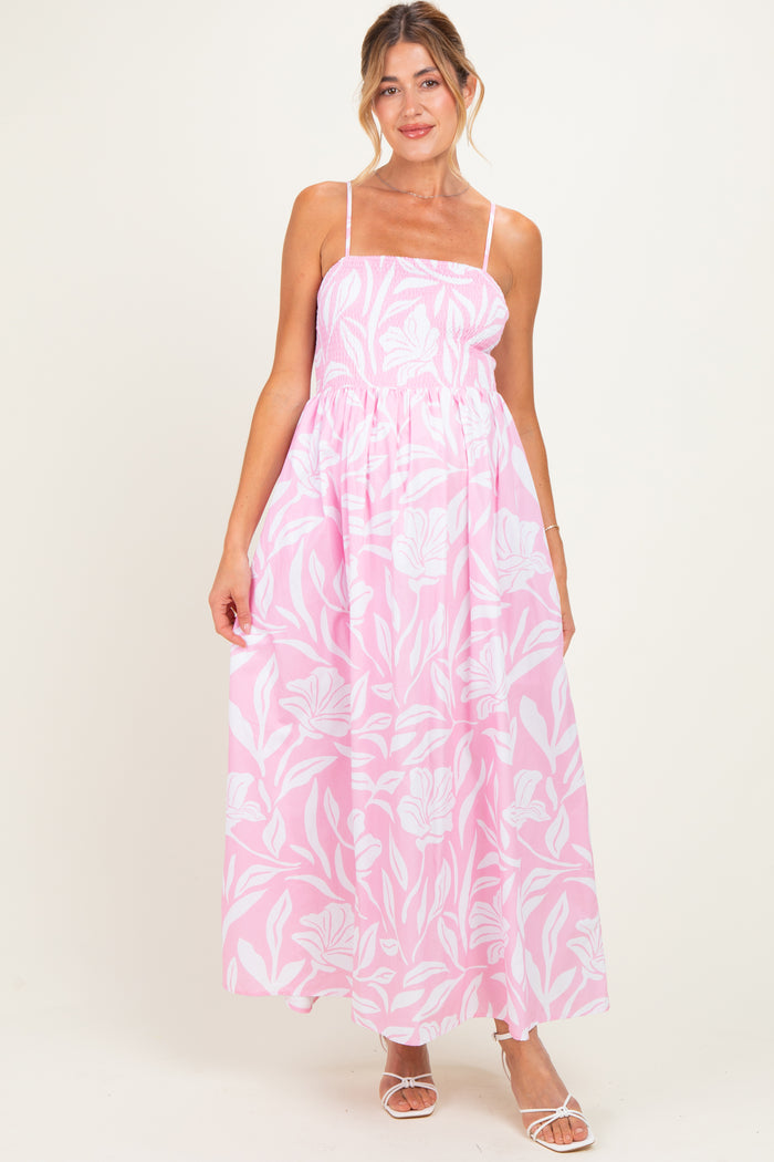 woman wearing a pink floral maternity maxi dress with spaghetti straps and a smocked bodice, showcasing a baby bump