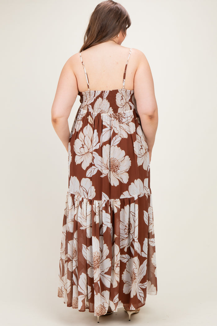 woman wearing a brown floral maternity maxi dress, showing the back view with adjustable straps and tiered skirt