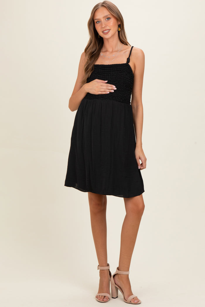 woman wearing a black maternity dress with smocked bust and spaghetti straps, holding her baby bump