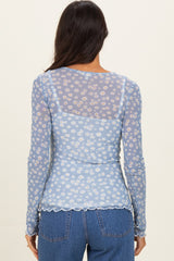 woman wearing a light blue floral sheer long sleeve top with scalloped hem and back design