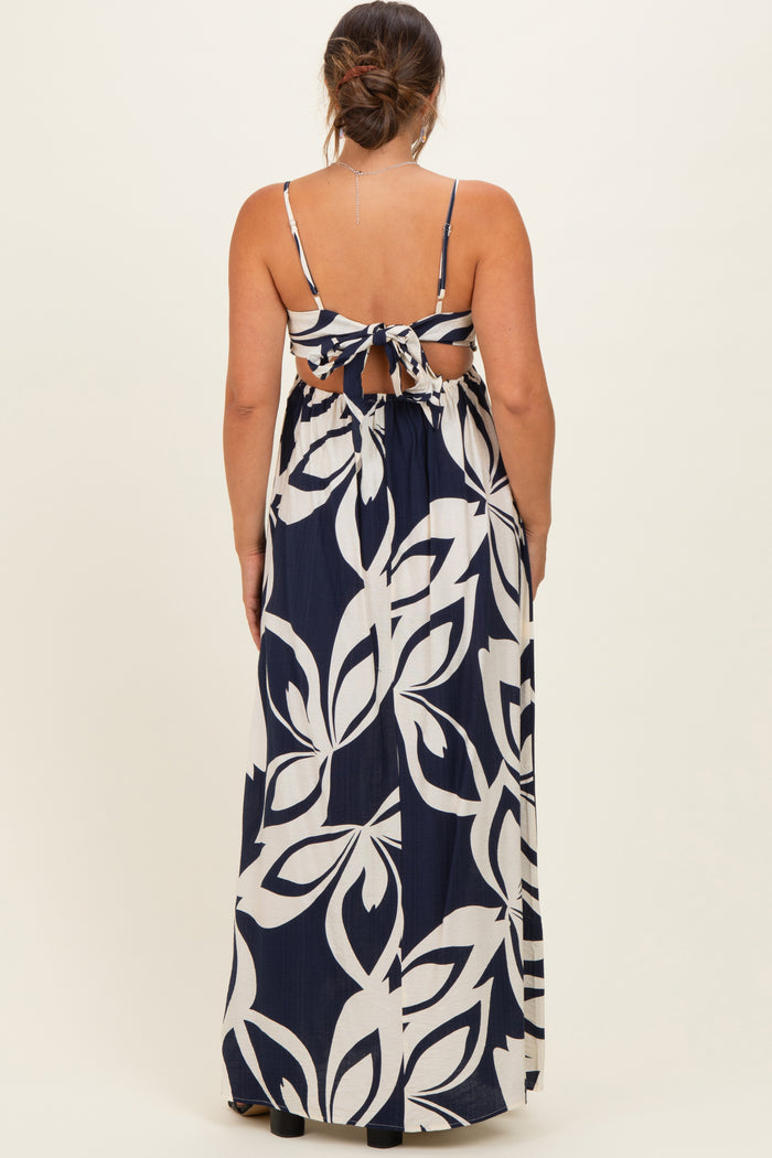 woman wearing a navy and white floral print maternity maxi dress with a tie-back detail