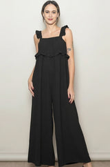 woman wearing a black sleeveless jumpsuit with ruffle details and wide legs