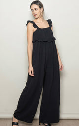 woman wearing a black ruffled jumpsuit with wide legs and adjustable straps