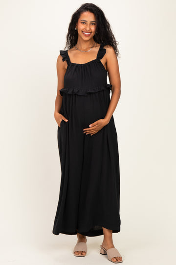 woman wearing a black maternity maxi dress with ruffled straps and holding her baby bump