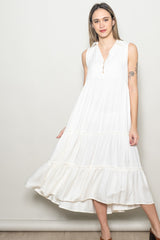 woman wearing a sleeveless white tiered maxi dress with a collar and button detail