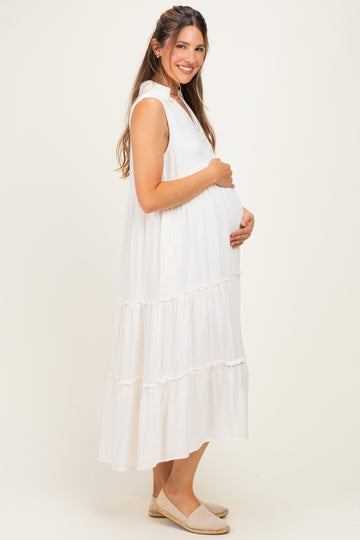 woman wearing a white tiered maternity dress and holding her baby bump