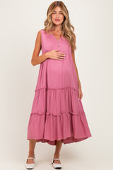 woman wearing a pink sleeveless maternity dress with tiered ruffles and holding her baby bump