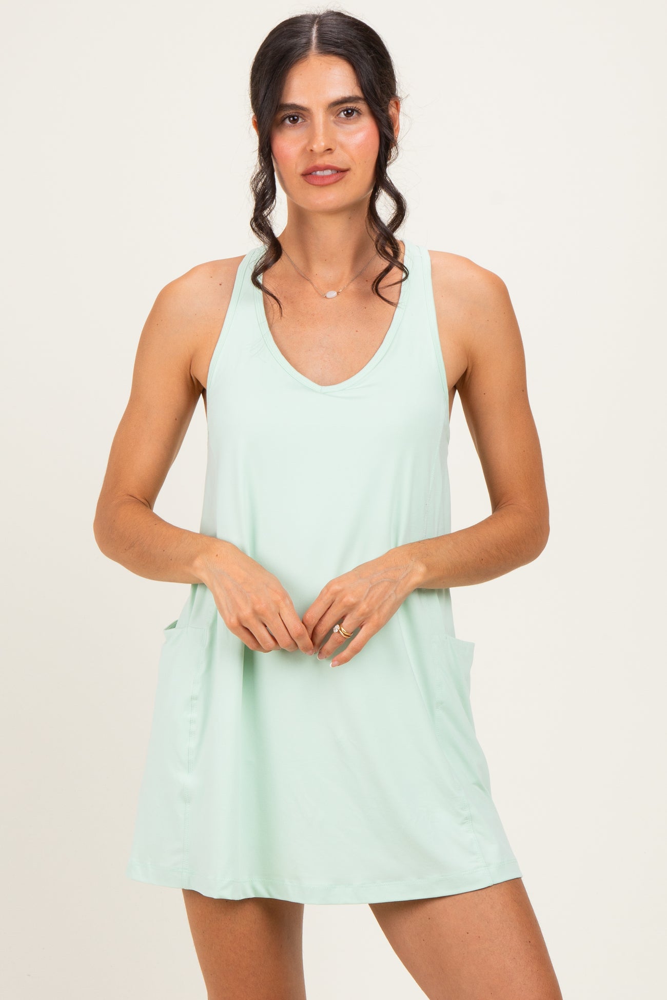 woman wearing a light green sleeveless dress with two side pockets and a relaxed fit