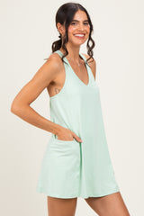 woman wearing a mint green sleeveless mini dress with a v-neck and side pockets