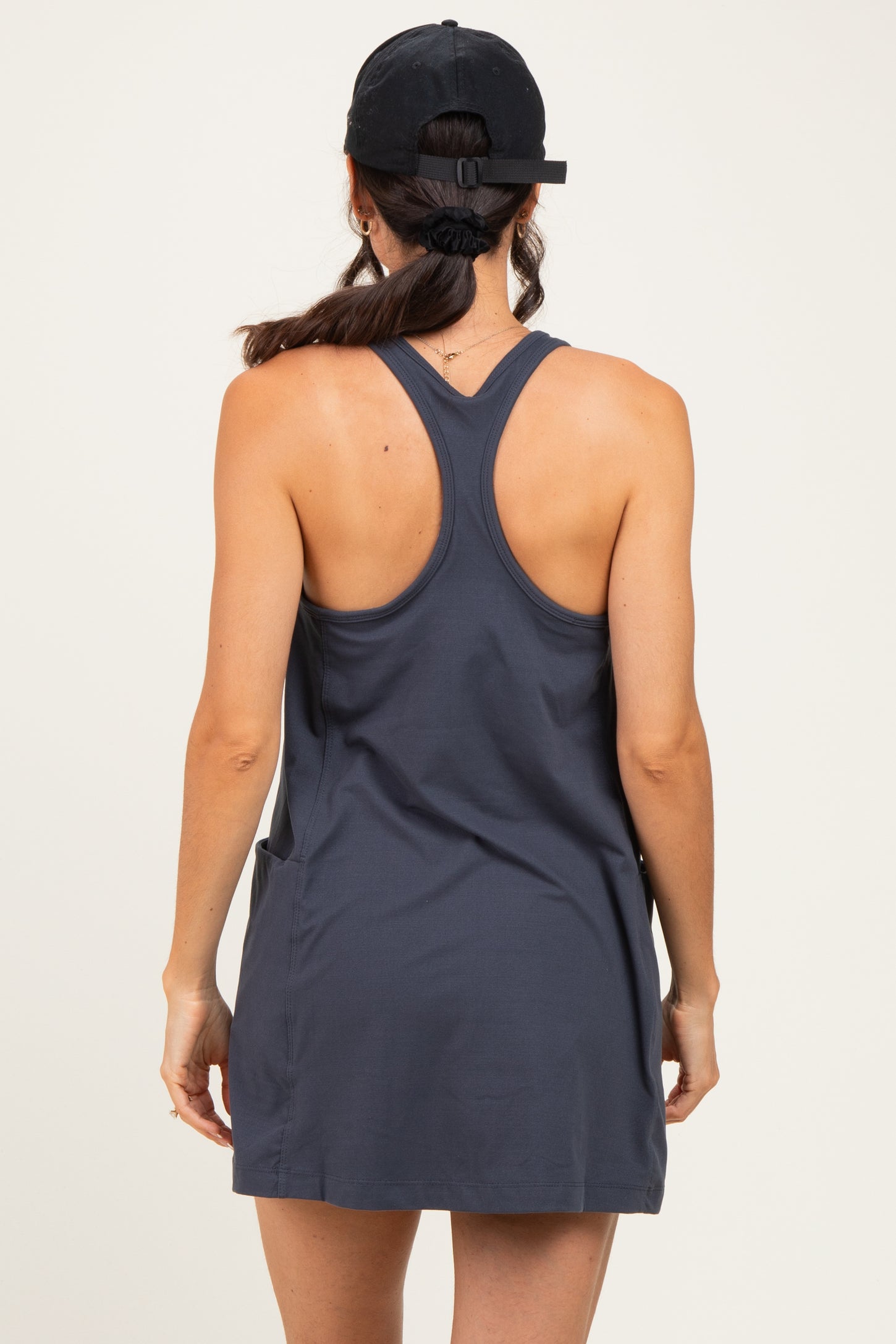 woman wearing a dark gray sleeveless dress with a racerback style, seen from the back