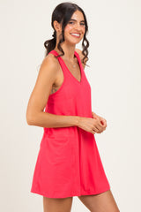 woman wearing a bright pink sleeveless shift dress with a v-neckline, smiling and standing sideways