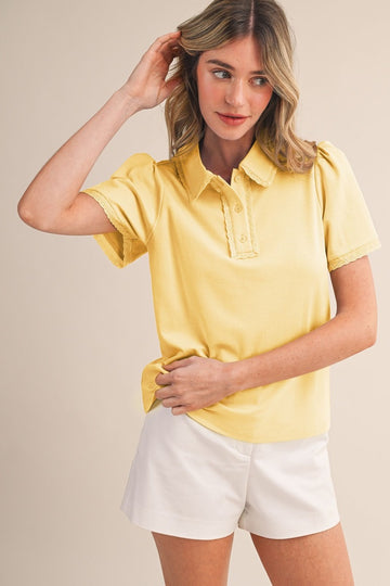 woman wearing a short sleeve yellow polo shirt with a collar and puff sleeves, paired with white shorts