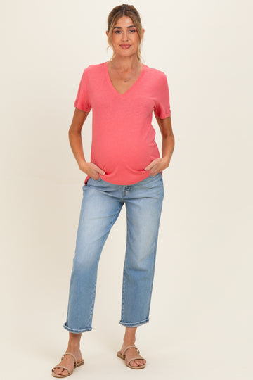 woman wearing a coral v-neck maternity t-shirt with pockets and light blue relaxed fit jeans, baby bump visible