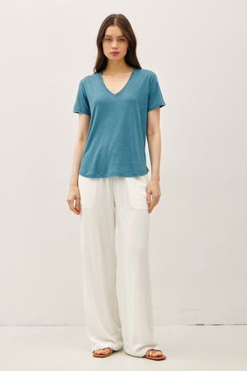woman wearing a teal short sleeve v-neck t-shirt and white wide-leg pants