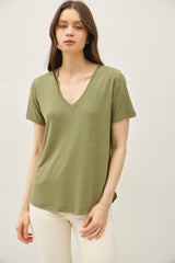 woman wearing an olive green v-neck t-shirt paired with white pants