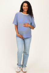 woman wearing a blue and white striped maternity t-shirt and light jeans, gently cradling her baby bump