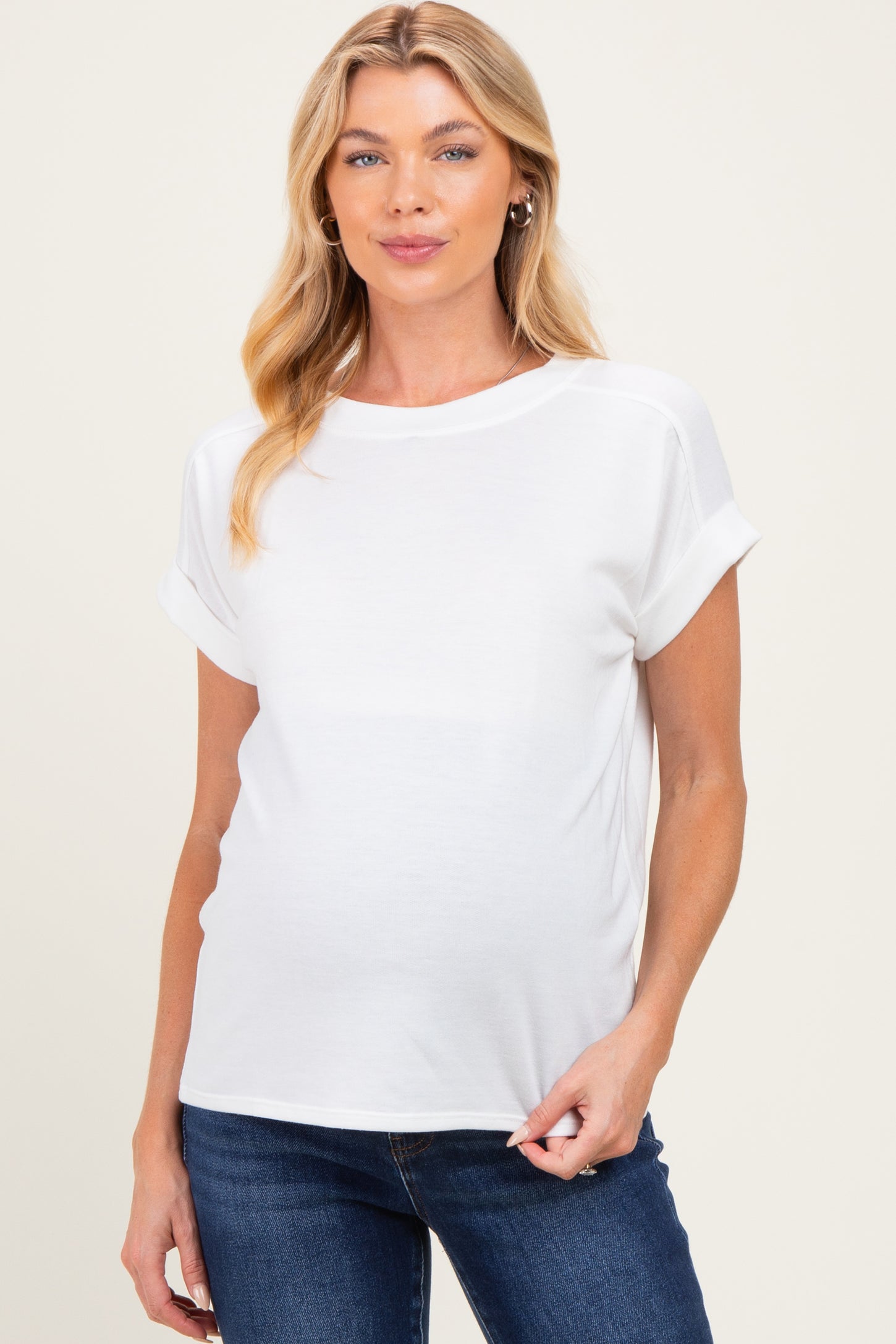 woman wearing a white maternity top with rolled sleeves and a visible baby bump