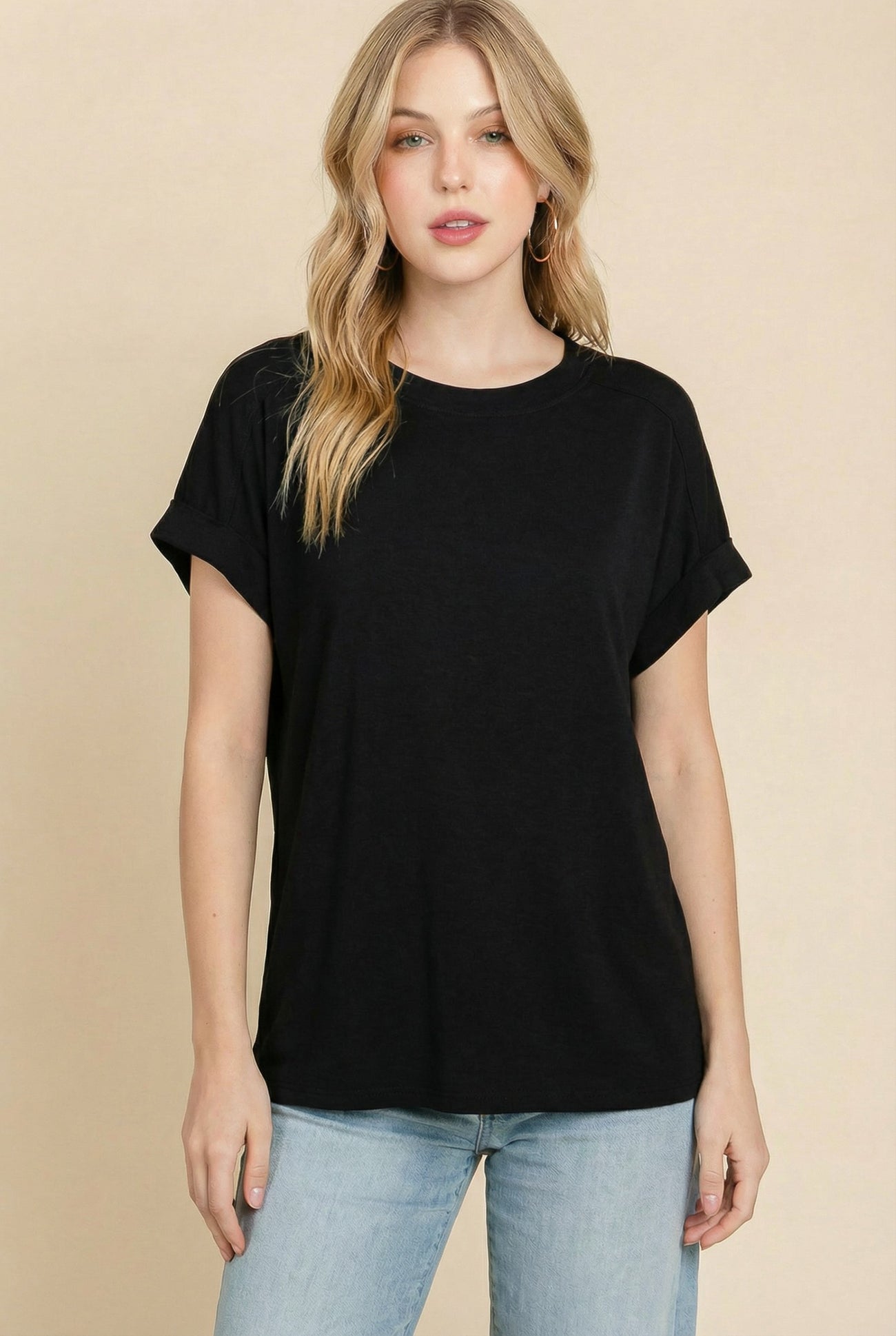 woman wearing a black short sleeve t-shirt with rolled cuffs and relaxed fit, paired with light blue jeans