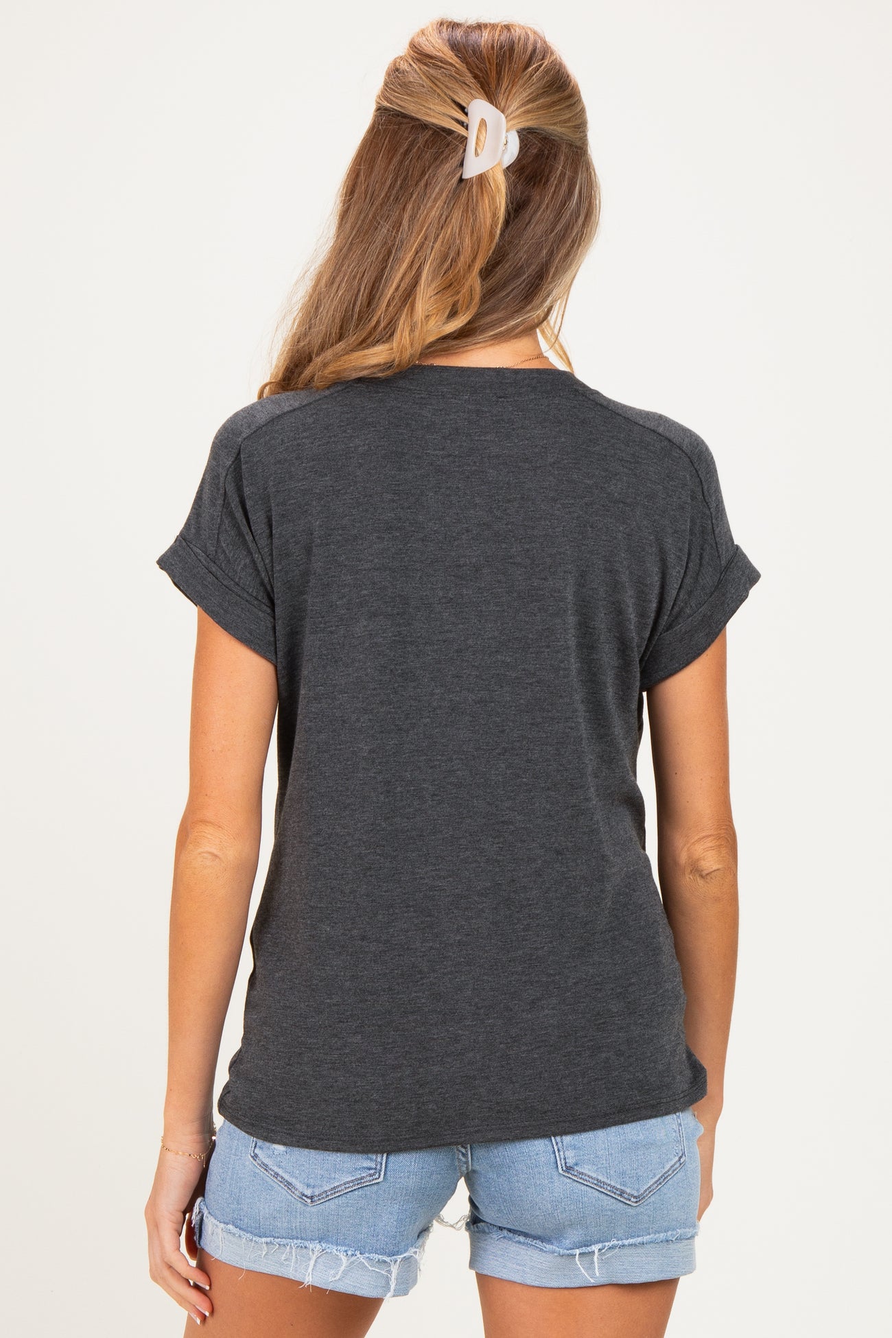 woman wearing a dark gray short sleeve maternity top with rolled cuffs and light blue denim shorts