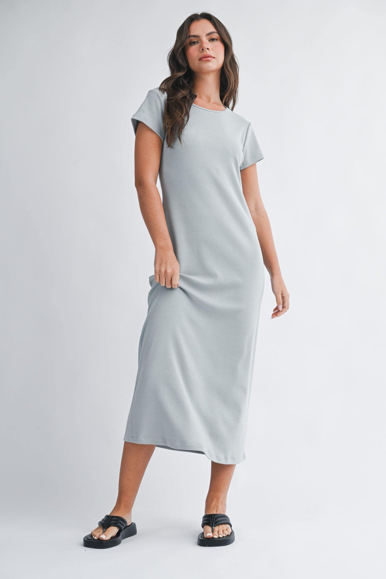 woman wearing a light gray short sleeve maxi dress and black sandals