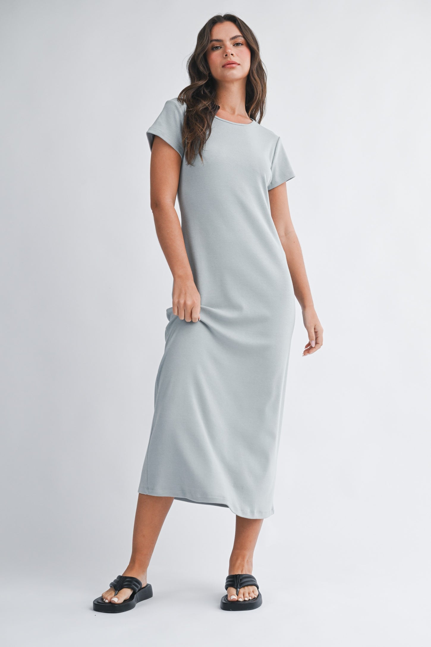woman wearing a light gray short sleeve maxi dress and black sandals