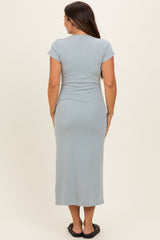woman wearing a light blue short sleeve maternity dress, showing a fitted style from the back