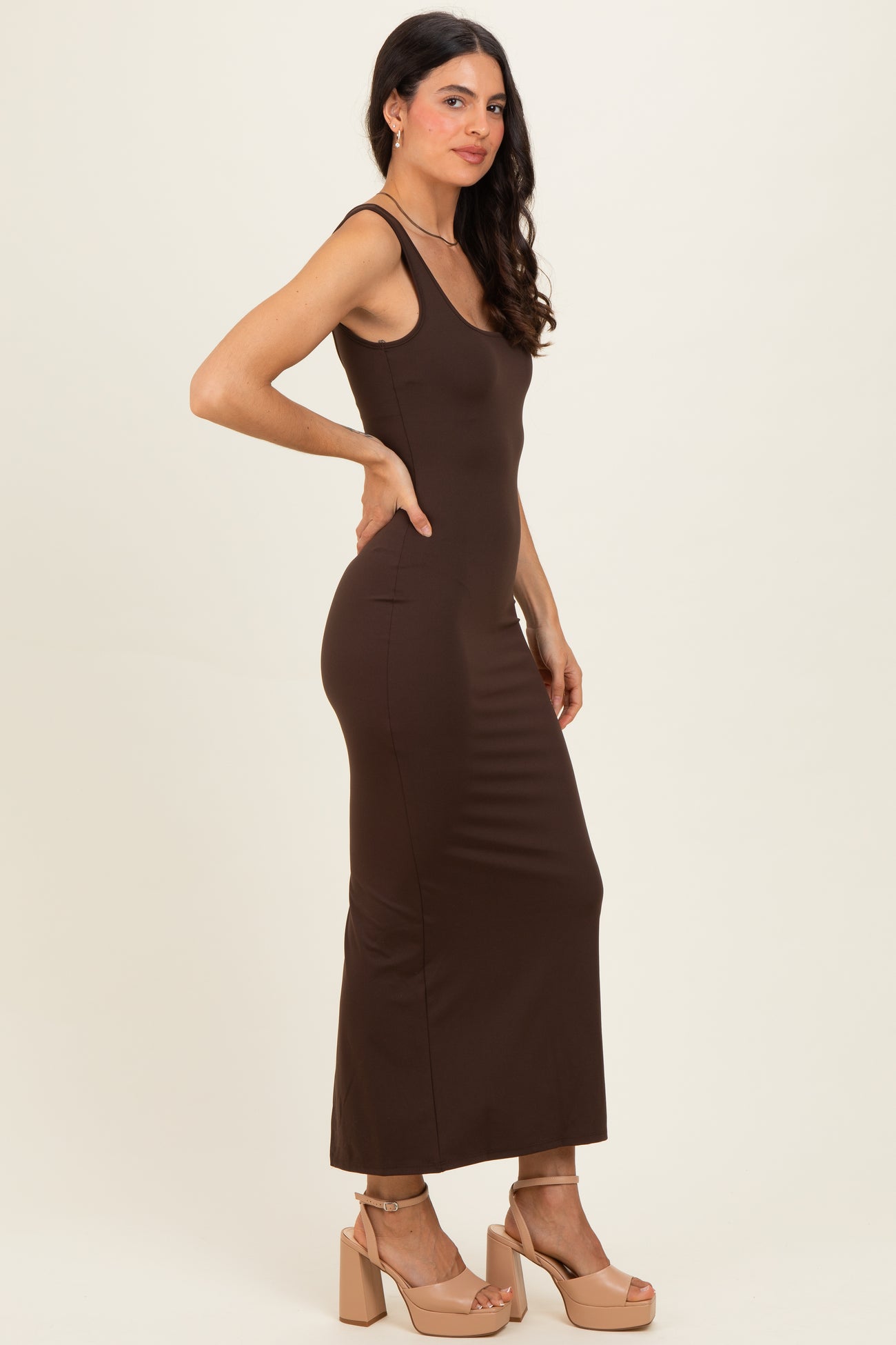woman wearing a brown fitted maxi dress with thin straps and high heels