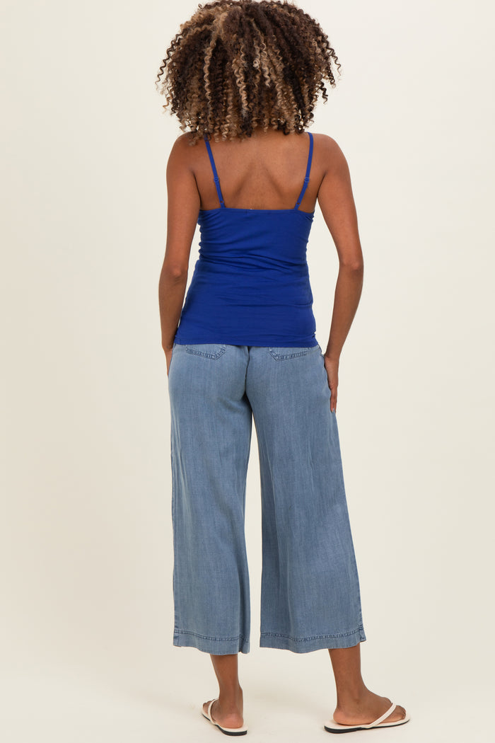 woman wearing a blue maternity tank top and light blue wide-leg jeans, seen from the back