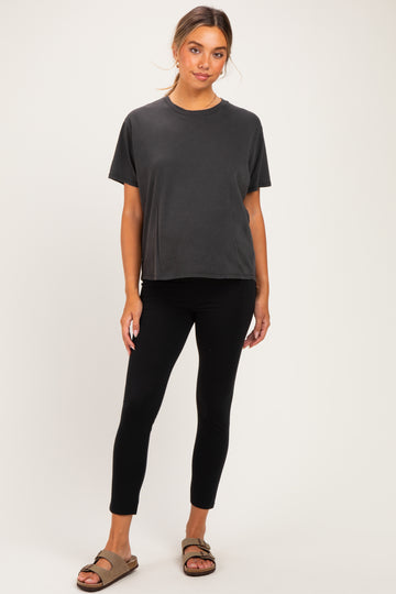 woman wearing a black maternity top and black maternity leggings, standing with a relaxed pose