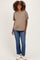 woman wearing a taupe maternity top with short sleeves and blue straight-leg jeans