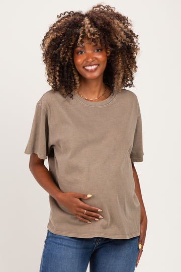 woman wearing a brown oversized maternity t-shirt and holding her baby bump