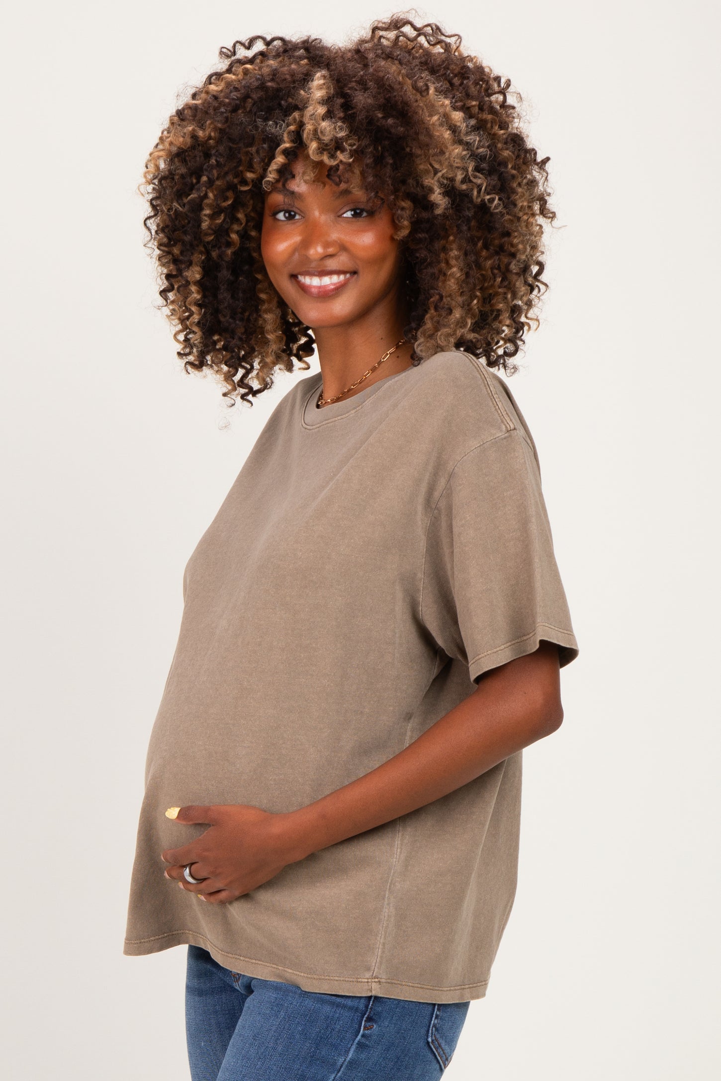 woman wearing a taupe oversized short sleeve maternity t-shirt and holding her baby bump