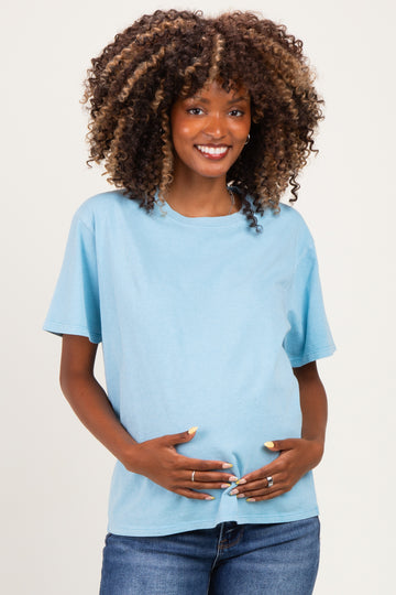 woman wearing a light blue short sleeve maternity top and holding her baby bump