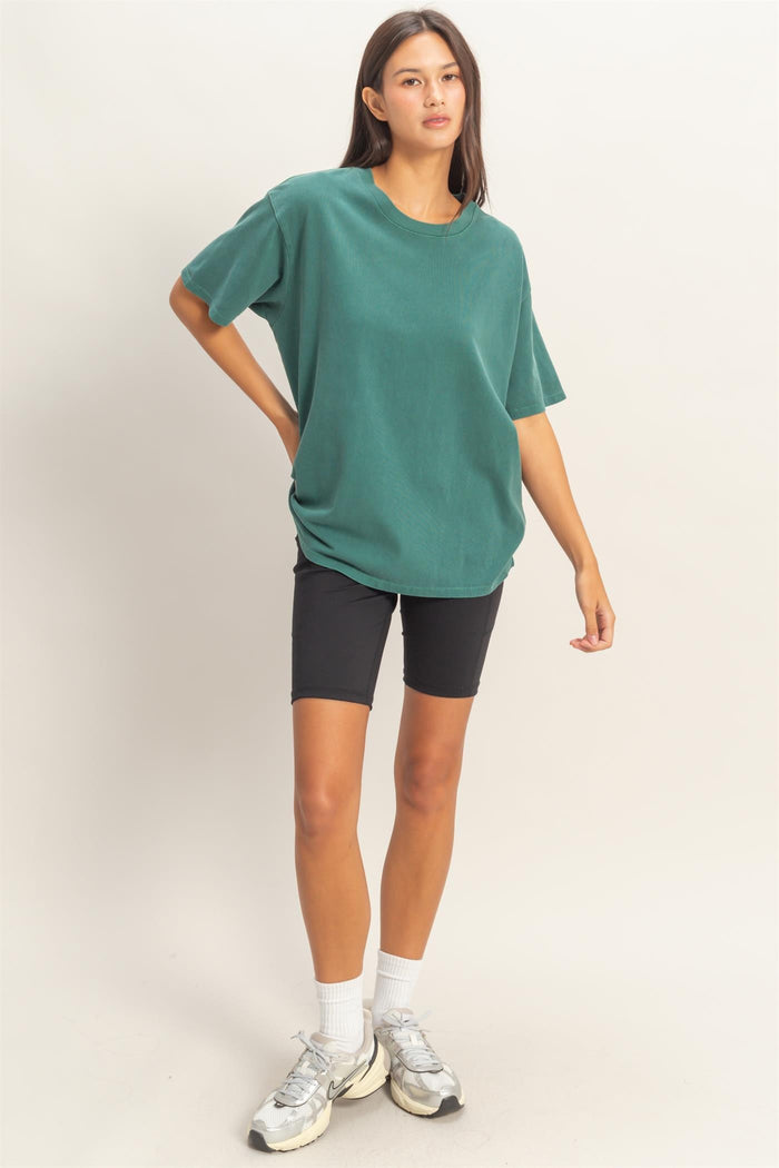 woman wearing a green oversized t-shirt and black bike shorts with white socks and sneakers