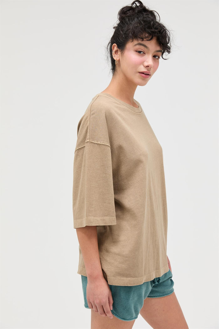 woman wearing a tan oversized t-shirt with short sleeves and styled with teal shorts