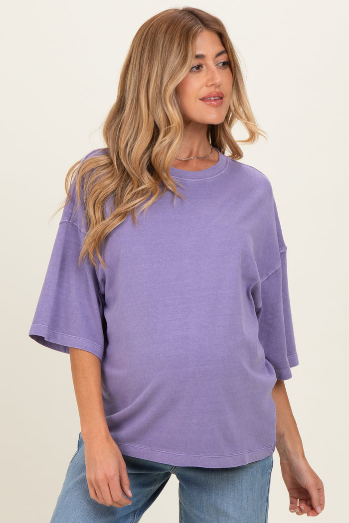 woman wearing a purple oversized maternity top and showing her baby bump